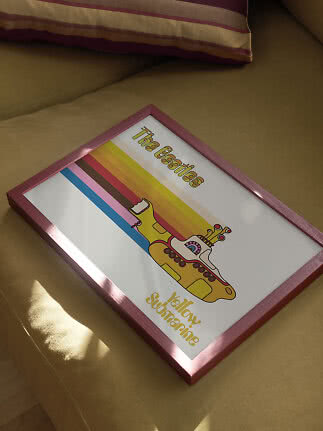 Gerahmtes Yellow-Submarine-Poster mit The-Beatles-Motiv auf senffarbenem Sofa