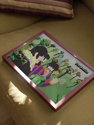 Gerahmtes Beatles-Poster mit bunter Illustration, liegend auf einem gelben Sofa