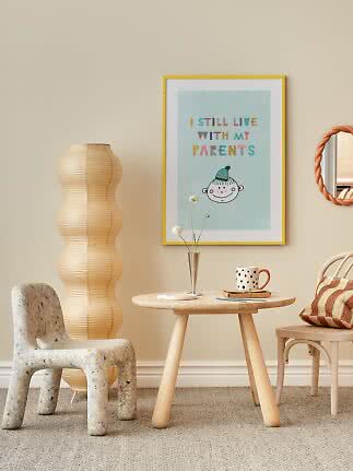Kids' room with framed poster, round table, chair, paper floor lamp and polka dot mug