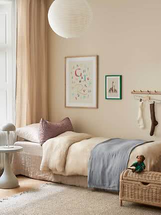 Cozy kids' bedroom with single bed, paper lantern, wall art and woven storage bench