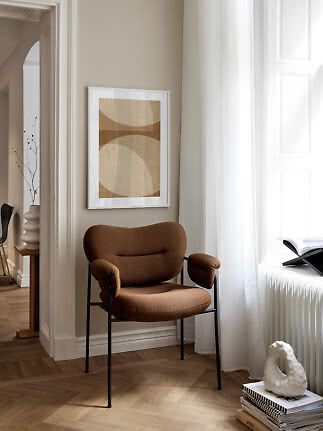 Brown upholstered armchair by window with abstract print on beige wall