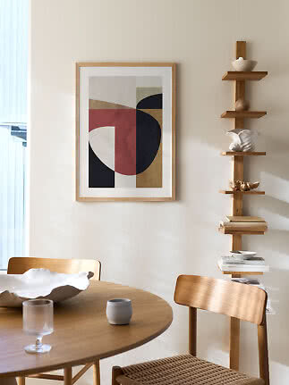 Ingelijste abstracte poster met geometrische vormen boven een houten eettafel