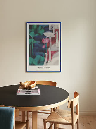 Indrammet plakat med hvide flamingoer og pink lotusblomst over rundt sort spisebord