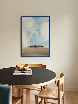 Abstrakt maleri i blå og beige toner i blå ramme over rundt spisebord med træstole.
