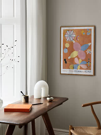 Indrammet Hilma af Klint-plakat med abstrakte blomsterformer på beige væg over et træskrivebord