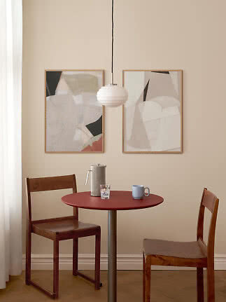 White ribbed pendant lamp above a round red table with two wooden chairs in a light dining nook