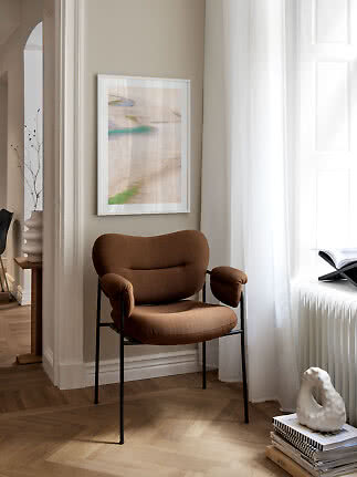 Brown upholstered chair with black legs in a bright corner by the window