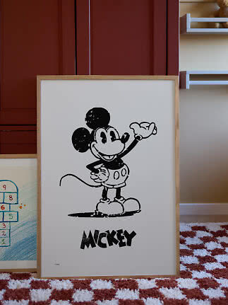 Ingelijste zwart-witte Mickey Mouse-poster, leunend tegen de muur in een kinderkamer