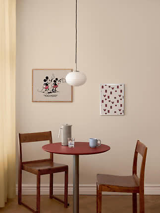Eethoek met rode ronde tafel, twee houten stoelen en witte hanglamp