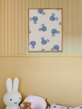 Ingelijste abstracte poster met blauwe cirkels op witte achtergrond boven een bed in een kinderkamer