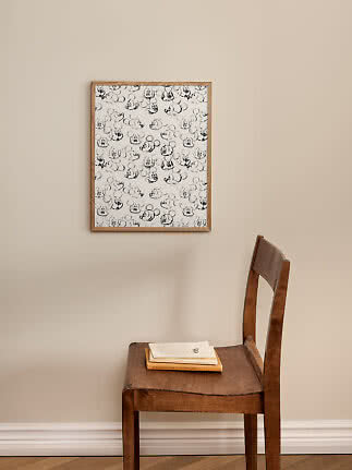 Ingelijste zwart-wit poster met Mickey Mouse-schetsen boven een houten stoel met boeken.