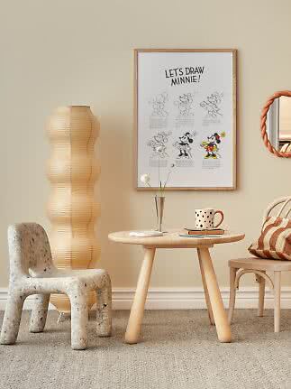 Ingelijste Minnie Mouse-poster boven ronde houten tafel in gezellige kinderkamer