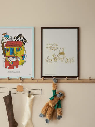 Zwei gerahmte Kinderposter auf einer Holzleiste über Socken und einem hängenden Kuschelaffen.