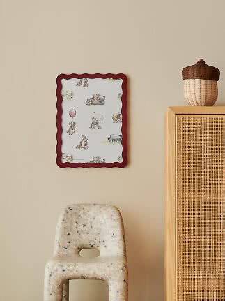 Kinderposter mit gewelltem rotem Rahmen und Winnie-Puuh-Motiven an beigefarbener Wand