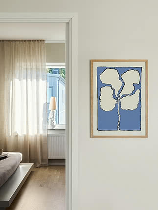 Stampa astratta incorniciata con sfondo blu e fiore bianco su parete beige accanto alla porta