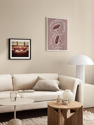 Moderne stue med hvid sofa, træbord, hvid lampe og to indrammede kunstværker på beige væg