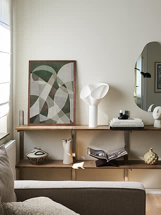 Wohnzimmer mit Holzregal, abstrakter Kunst, weißer Tischlampe, Spiegel und Dekovasen