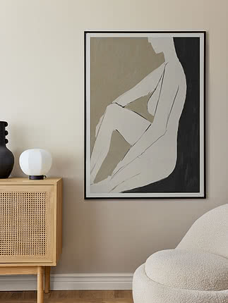 Framed abstract poster of a seated figure in beige, white and black on a wall