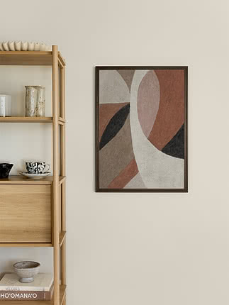 Quadro astratto dai toni caldi della terra con cornice scura accanto a una mensola in legno chiaro