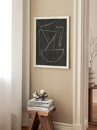Indrammet abstrakt sort plakat med hvide geometriske linjer på beige væg