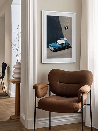 Framed poster of a blue vintage car seen from above, hanging on a light wall