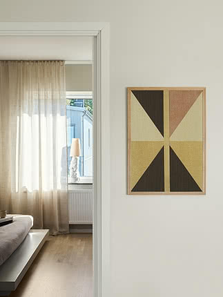Geometrisk plakat i egetræsramme på lys væg ved en soveværelsesdør
