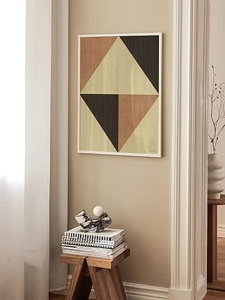 Geometrisk plakat i hvid ramme i en entré over en valnøddeskammel med magasiner