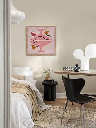 Stampa Out of Vase Blooms III in cornice di rovere su parete beige in camera, sopra un tavolino nero e un letto in lino
