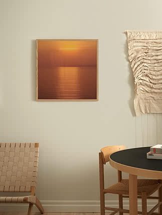 Stampa Still Copper in cornice di rovere su parete greige, accanto a un macramè crema appeso e a una sedia in pelle cuoio