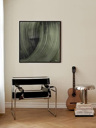 Stampa Sage Brush in cornice nera su parete crema, sopra una poltrona in pelle nera e cromo accanto a una chitarra