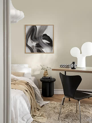 Stampa Tempest Noir 01 in cornice di rovere su parete beige in camera, sopra un tavolino nero accanto a un letto in lino