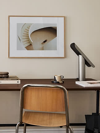 Poster Helix im Eichenrahmen mit weißem Passepartout an beiger Wand über einem dunklen Nussbaumschreibtisch mit Bugholzstuhl und silberner Lampe