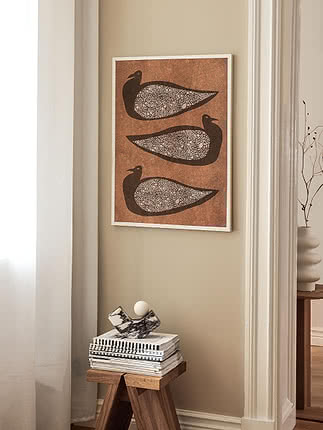 Trycket Textured Birds i vit ram på beige vägg i en smal nisch ovanför en träpall med böcker