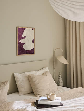 Tirage Flying White Dove dans un cadre en chêne sur un mur de chambre beige au-dessus d'un lit aux coussins crème et d'une applique
