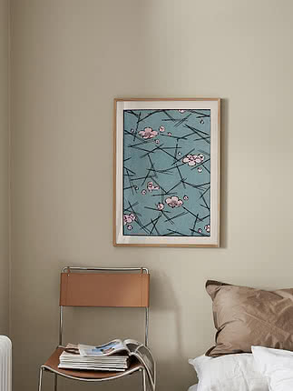 Affiche Flowers on Ice dans un cadre en chêne au-dessus d'un lit, près d'une chaise en cuir fauve avec des magazines