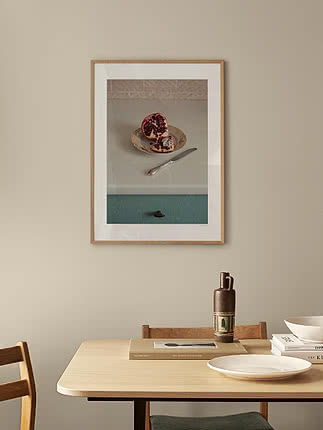 Postern Split Fruit i ekram på beige vägg ovanför ett matbord i ljus ek med tallrikar och en keramikvas