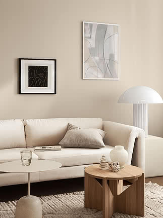 Trykket Neutral Canvas i hvid ramme på en beige væg ved siden af et mindre sortindrammet tryk over en cremefarvet sofa