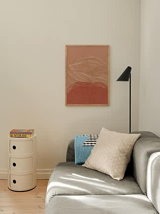 Druck Desert Horizon im Eichenrahmen an beiger Wand über einem salbeigrünen Sofa neben einem weißen zylindrischen Beistelltisch