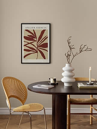 Plakaten Scarlet Leaves i sort ramme på beige væg over et rundt mørkt spisebord med hvid riflet vase, et lys og bøjetræsstole