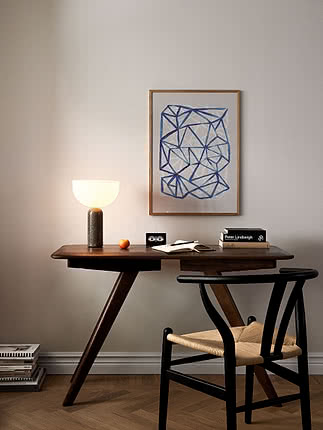 Trykket The Grid i egeramme på en beige væg over et mørkt træskrivebord med en glaskuppellampe og bøger