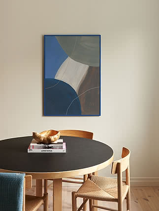 Druck Harmony in Blue im blauen Rahmen an cremefarbener Wand über einem schwarzen runden Esstisch mit Papierkordelstühlen