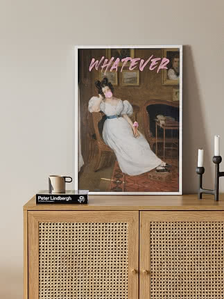 Plakaten Whatever Sassy i hvit ramme lent mot et skjenk i eik med rattandører, med et krus i steingods, en fotobok og en svart lysestake med hvite lys