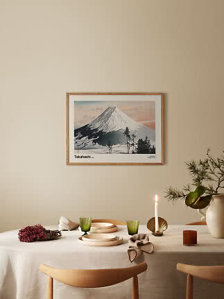 Stampa d’arte incorniciata con montagna innevata sopra una tavola apparecchiata con candela