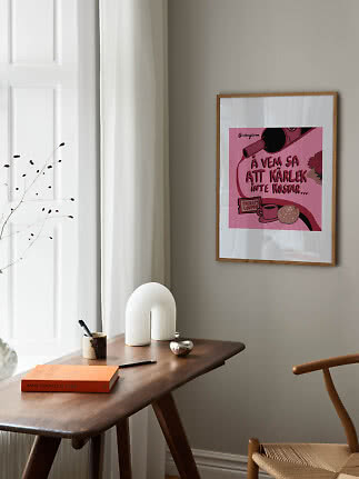 Affiche rose encadrée au-dessus d’une table en bois près d’une fenêtre dans une pièce épurée