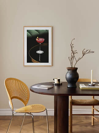 Indrammet plakat af pink cocktailglas på væg over spisebord