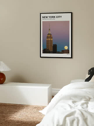 Inramad New York City-poster med Empire State Building och fullmåne på beige sovrumsvägg