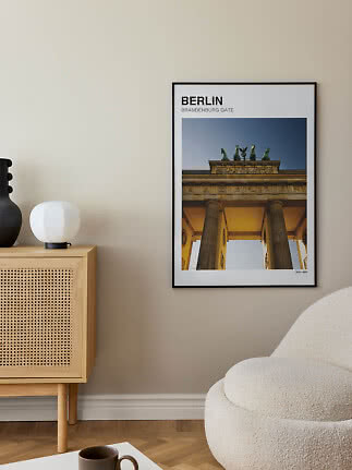 Framed Berlin poster with Brandenburg Gate on a beige wall in a modern living room