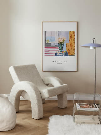 Matisse-plakat i lys træramme hænger over en cremefarvet lænestol i et stilrent hjørne.