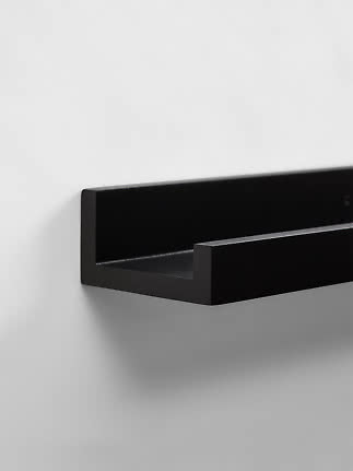 Czarna metalowa półka ścienna o minimalistycznym designie na białej ścianie