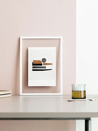 White framed abstract print with geometric shapes on a table against a blush pink wall
